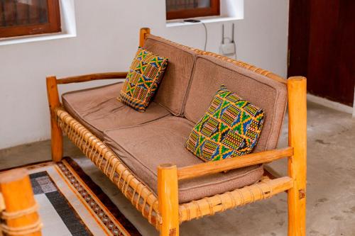 ein braunes Sofa mit drei Kissen darauf in der Unterkunft The Hub Train House Apartments in Zanzibar City