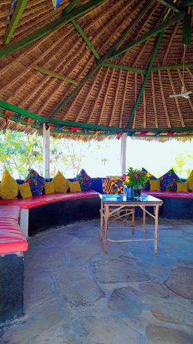 una zona salotto con tavolo e tetto di paglia di HIGSAM apartment a Diani Beach