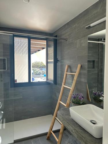 a bathroom with a wooden ladder next to a sink at Villa Groovy in Lajares