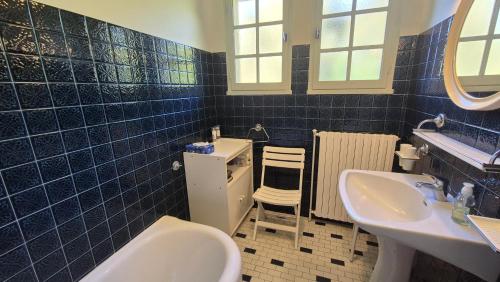 a blue tiled bathroom with two sinks and a toilet at Verte Rive – Maison climatisée en bord de Dordogne in Cénac-et-Saint-Julien