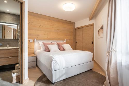 Un dormitorio con una cama blanca y una pared de madera. en Apartment Cumbre Alpe d'Huez - by EMERALD STAY, en LʼHuez