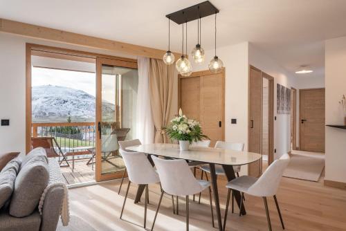 Un comedor con una mesa y sillas y un sofá. en Apartment Cumbre Alpe d'Huez - by EMERALD STAY, en LʼHuez