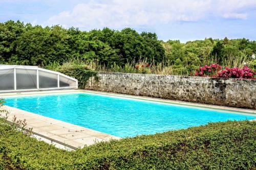 a swimming pool in a garden with a stone wall at Gîte Gué Léger - Nature & Spa - Jacuzzi, Sauna - Piscine chauffée toute l'année - 15 pers in Chanceaux-près-Loches