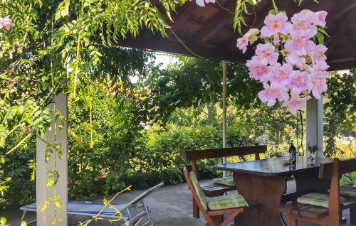 einen Tisch und Stühle unter einer Pergola mit rosa Blumen in der Unterkunft Lovely Apartment In Mali Ston With Wifi in Mali Ston
