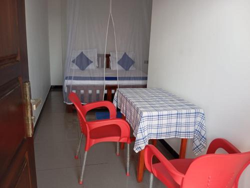 a dining room with a table and red chairs at Sunset Beach Villa in Galle