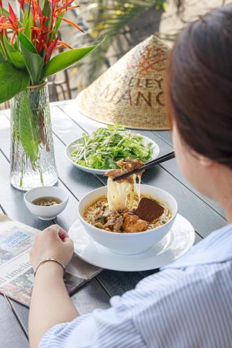 Valley De Mango Hue في Thôn Châu Chữ: امرأة تجلس على طاولة مع وعاء من الطعام