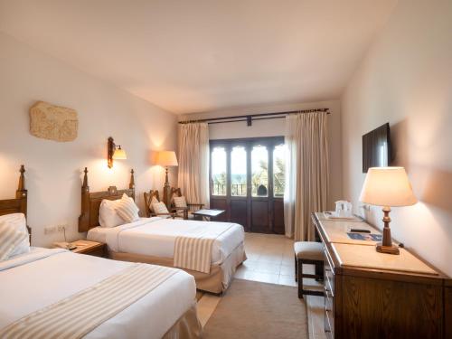 a hotel room with two beds and a desk at Sunny Days El Palacio Resort & Spa in Hurghada