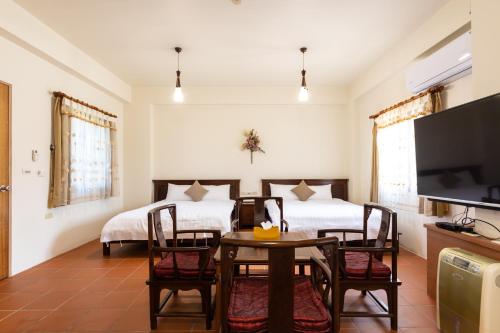 a room with two beds and a table and a tv at 宜蘭閑居民宿 in Suao