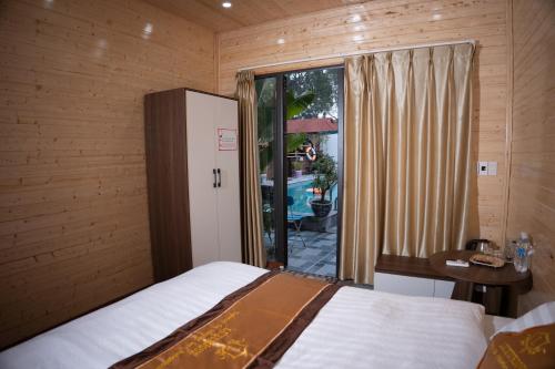 a bedroom with a bed and a table and a window at Tamcoc De Master Lux Bungalow in Ninh Binh
