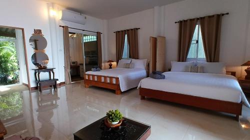 a bedroom with two beds and a living room at Tropical Sea Front House in Ko Po