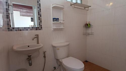 a white bathroom with a toilet and a sink at Tropical Sea Front House in Ko Po