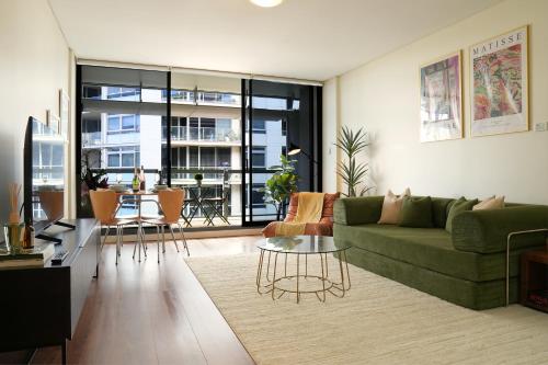 a living room with a green couch and a table at Modern Barangaroo Apartment with Waterfront Balcony Views & Private Parking in Sydney