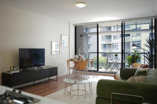 a living room with a couch and a tv at Modern Barangaroo Apartment with Waterfront Balcony Views & Private Parking in Sydney