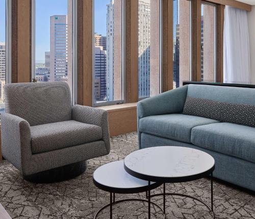 Sheraton Denver Downtown Hotel في دنفر: غرفة معيشة مع أريكة وكرسي وطاولات