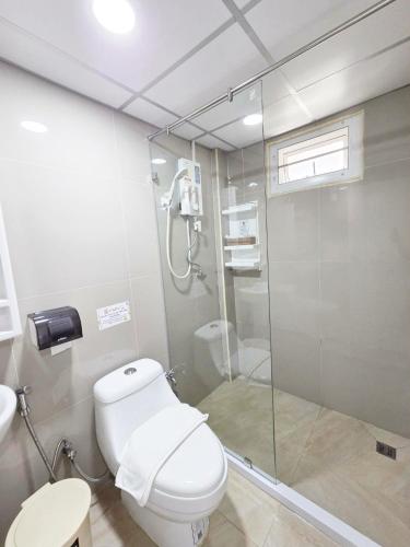 a bathroom with a toilet and a glass shower at PT Grand Hotel in Ban Tha Makham