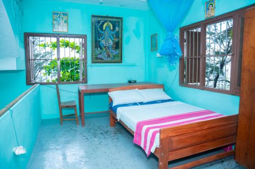 a blue bedroom with a bed and a desk at Thapovanam Veedu in Allaippiddi