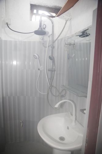 a white bathroom with a shower and a sink at Wood Aura Ella in Ella
