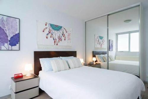 Brunswick Convenience 1BR Home في ملبورن: غرفة نوم بيضاء مع سرير كبير ومرآة