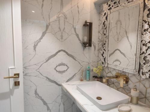 a bathroom with a white sink and a marble wall at Beach villa South Goa in Arossim-Cansaulim