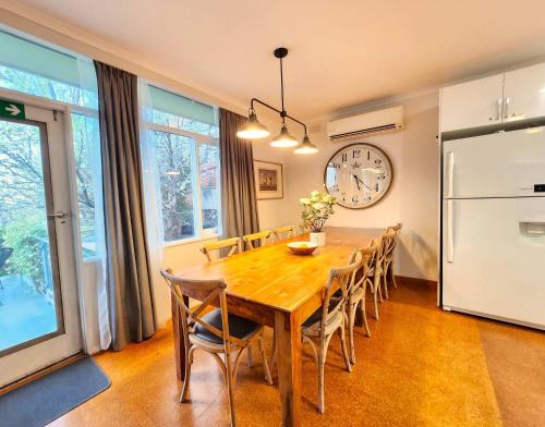 5 bedroom suite sleeps 16 with fully equipped kitchen & two bathrooms في Highett: طاولة طعام مع كراسي وساعة على الحائط