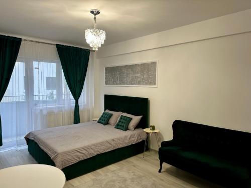 a bedroom with a bed and a couch and a chandelier at Romantic studio AxS in Floreşti