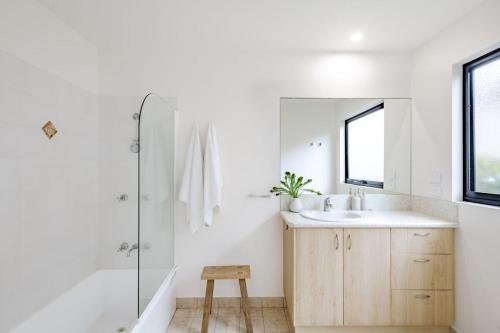 a bathroom with a sink and a mirror and a stool at Curragudde Cove - Pambula Beach in Pambula Beach
