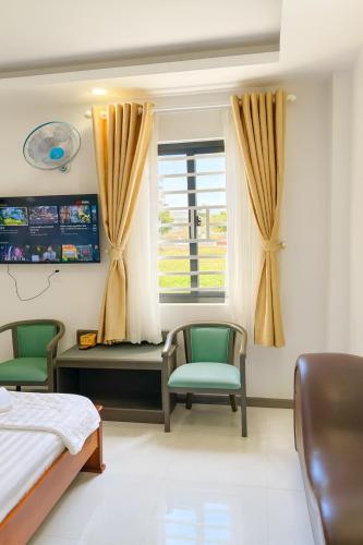 ein Schlafzimmer mit zwei Stühlen und einem Bett und einem Fenster in der Unterkunft Hạ Vy Hotel Hồ Chí Minh in Ho-Chi-Minh-Stadt