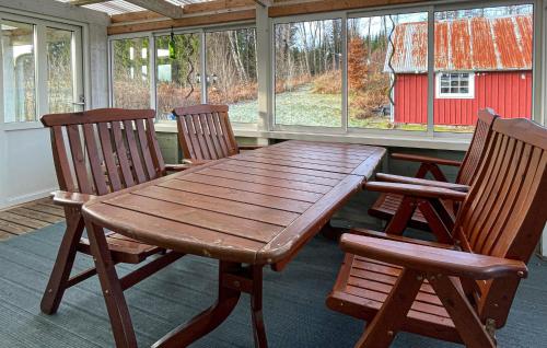 a wooden table and two chairs on a porch with a red barn at Stunning Home In Mårdaklev With Wifi in Boda