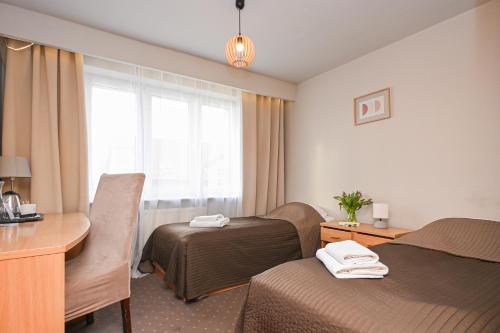 una camera d'albergo con due letti, una scrivania e una finestra di Hotel Dom Polonii a Ostróda