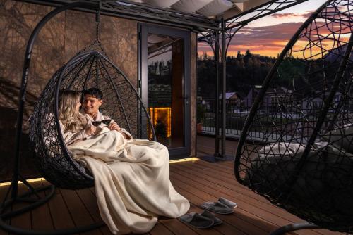 a bride and groom sitting in a swing on a balcony at Hotel Opinione Dimora Storica & Private Spa in San Lorenzo in Banale