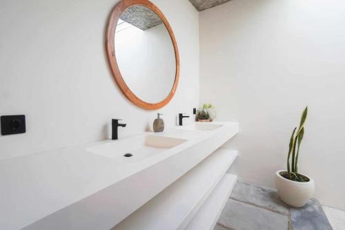 een witte badkamer met een wastafel en een spiegel bij Heliconia Joglo House in Sempidi