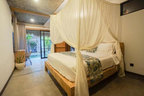 een slaapkamer met een hemelbed bij Heliconia Joglo House in Sempidi