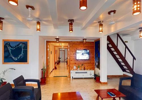Una sala de estar con una escalera y un sofá. en Asseyri Guest House, en Maradhoofeydhoo