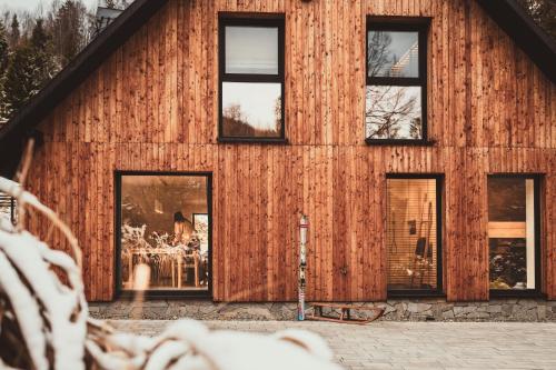 a woman sitting at a table in front of a building at Rycerki Dom na Szlaku in Rajcza