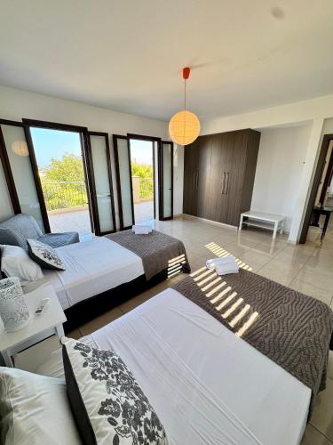 a bedroom with two beds and a large window at Aurora Gardens Villa Spacious 3 Bedroom in Protaras in Paralimni