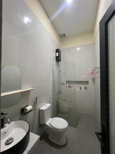 a white bathroom with a toilet and a sink at Villa indah sudungdewo in Wonosobo