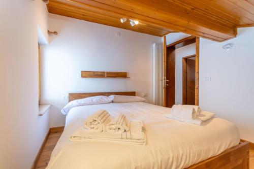 a bedroom with a large white bed with wooden ceilings at Sweet Loft in Sottoguda