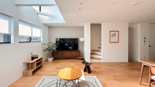 a living room with a table and a tv at USJ 梅田 大阪城へ直通 駐車場付きモダン一軒家 JR弁天町駅3分 LIRI Aoi in Osaka