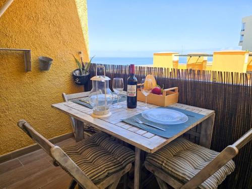 a table with two chairs and a bottle of wine at Arena Beach by HelloApartments in Puerto de Santiago
