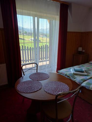 Una mesa y sillas en una habitación con ventana. en Pokoje Gościnne Murowanica, en Murzasichle