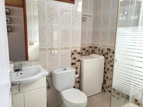 a bathroom with a toilet and a sink at Sunset Arena Beach by HelloApartments in Puerto de Santiago