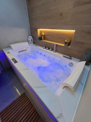 a bath tub with blue water in a bathroom at La Parenthèse Balnéo in Donzère