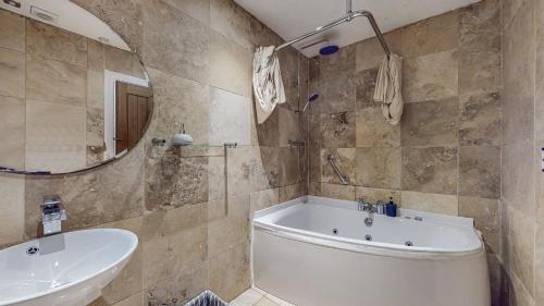 ein Badezimmer mit Badewanne, Waschbecken und Spiegel in der Unterkunft Finest Retreats - Old Barn at Ormidale House in Clachan of Glendaruel