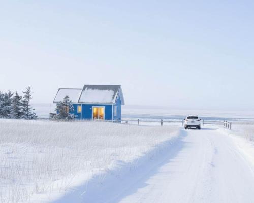 un'auto che percorre una strada innevata accanto a una casa blu di Coastal Charm Beach Nearby - Chalet Poirier a Fatima