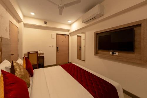 a hotel room with a bed and a flat screen tv at Gopuram Grand in Madurai