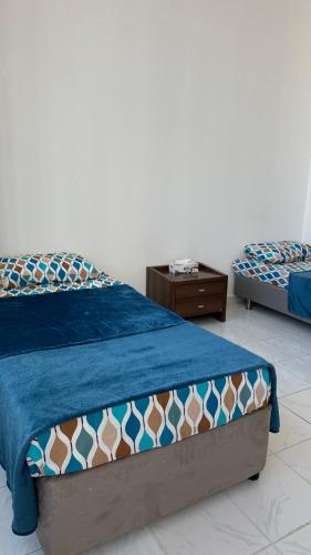 a bedroom with two beds and a night stand at Single bed space - Al Majaz 2 in Jazīrat al Ḩibāb