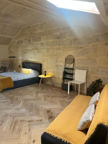 Maison Benoît في ازيس: غرفة نوم بها سرير وجدار حجري