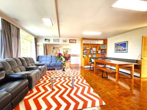 a living room with a couch and a table at Aloha Bayside 7 bedroom holiday house sleeps 23 Spa Sauna and Garden Views in Highett