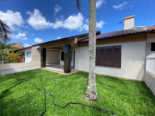 ein Haus mit einer Palme im Hof in der Unterkunft Fresh house enjoy the beach in the summer! in Capão da Canoa