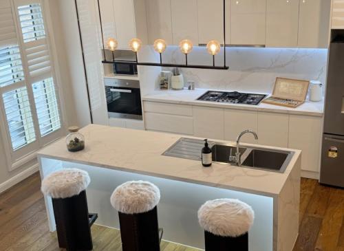 eine Küche mit Spüle und Theke mit Hockern in der Unterkunft Hampton Luxe Retreat 4BR Pet Friendly in Melbourne